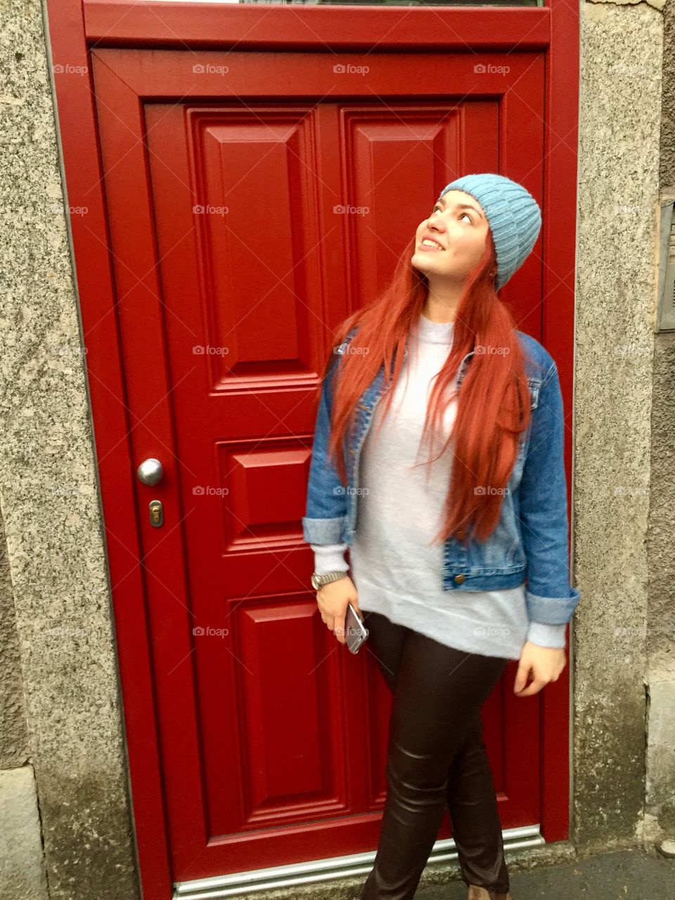 Redhead girl checking out a red misterious door.
