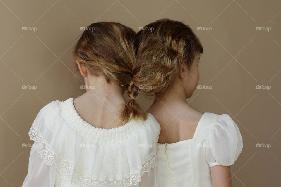 Two blonde little girls on a beige background 