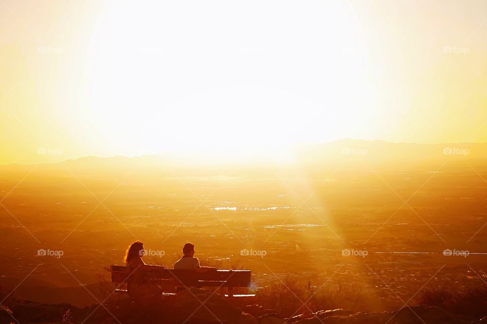 Two people on a bench at sunset