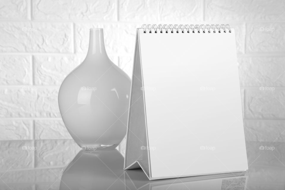 Blank white Calendar with a flower vase against white brick wall