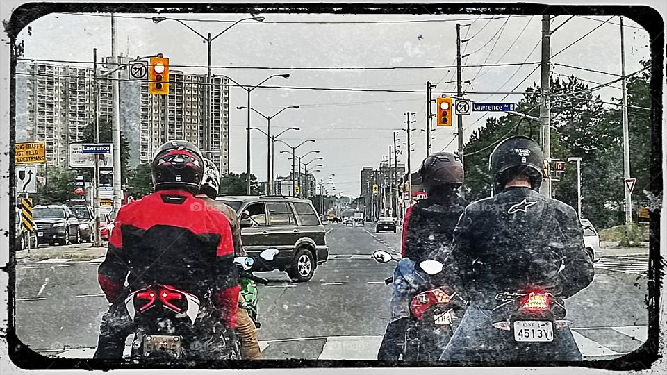 a gang of motorcycles sits patiently at a stoplight in Toronto.