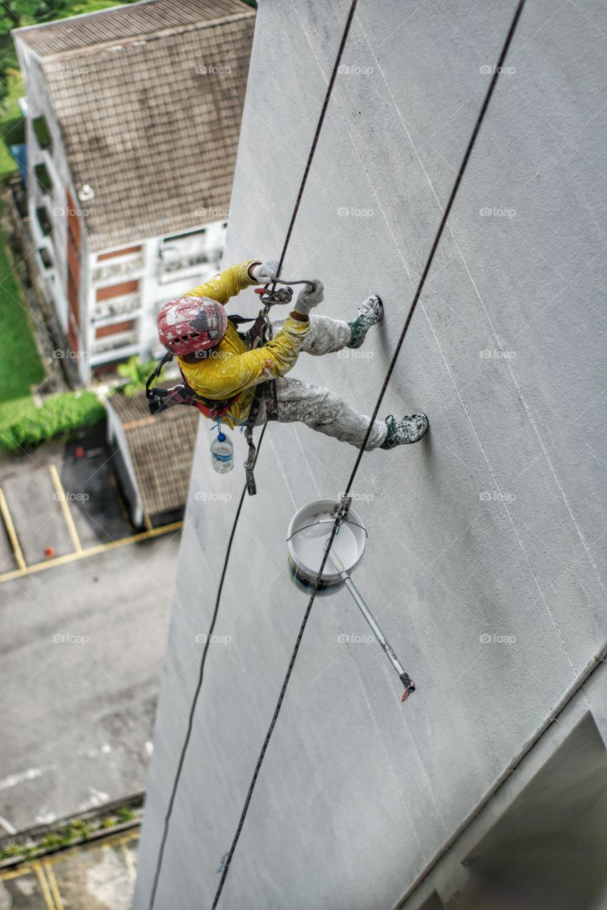 Worker abseiling down the side of a tower block in Kuala Lumpur Malaysia