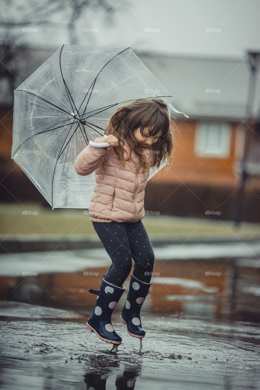 Little girl have fun under the rain.