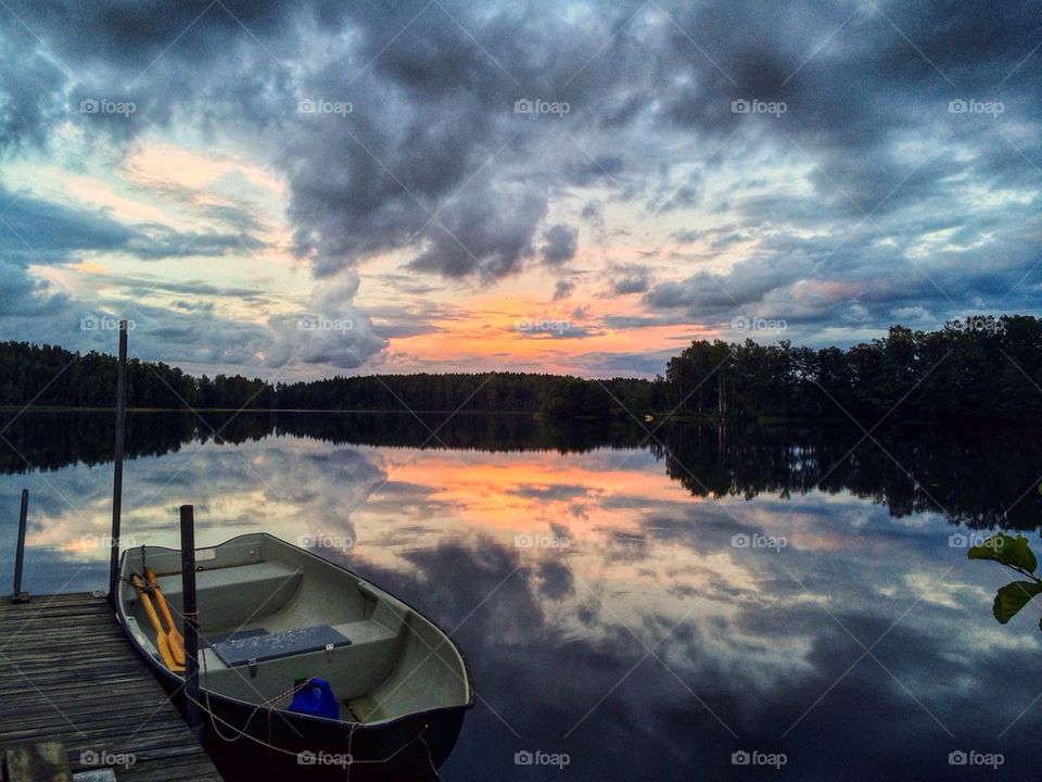 Boat moored on calm water at sunset