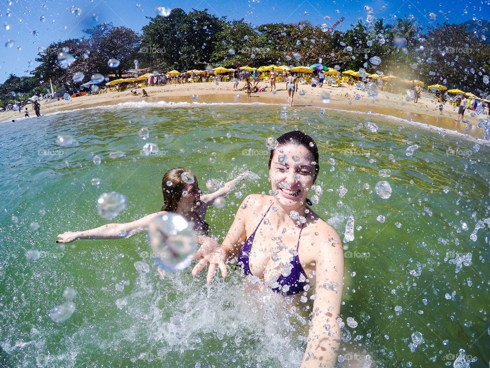 Two young women splashing water from swimming pool