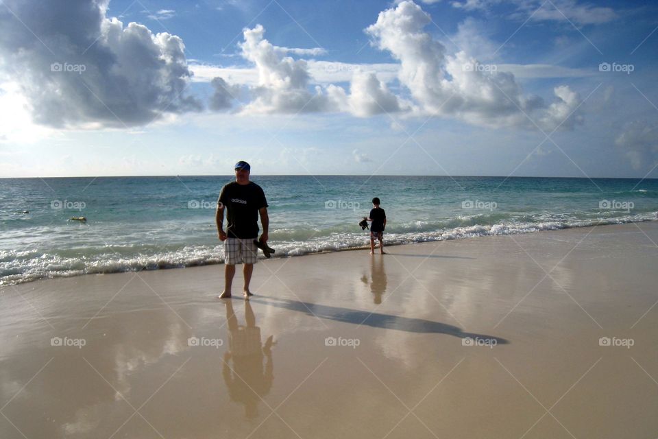 Awesome ocean photo of dad and son standing by the waters edge. 