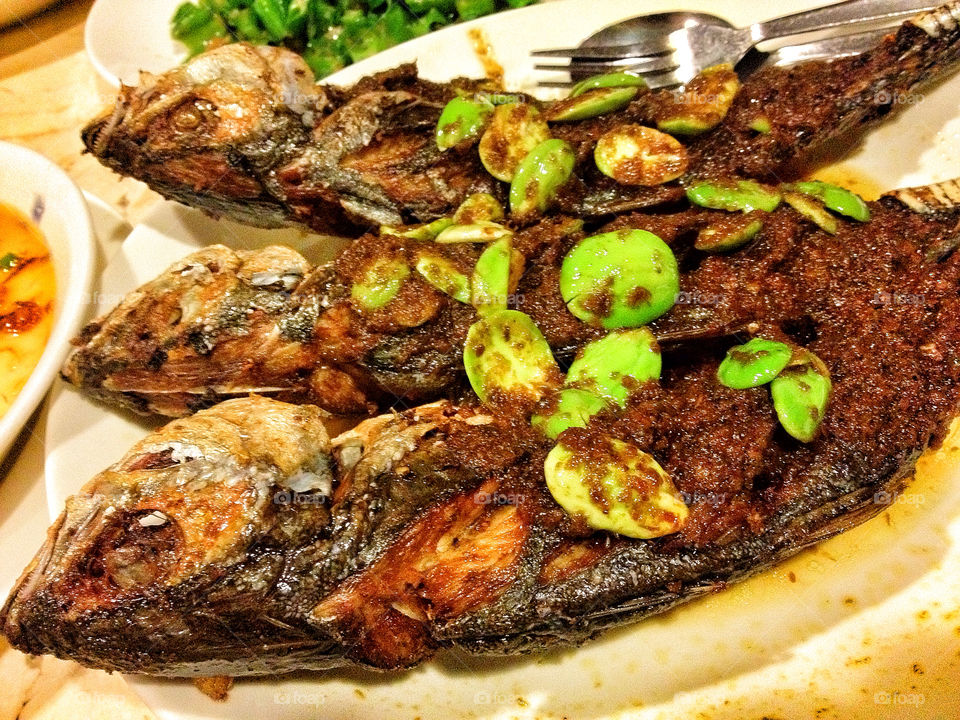 Traditional Malaysian dish of Scad fish (Malay: cencaru), stuffed with spice paste and deep fried, garnished with stink beans (Malay: petai)