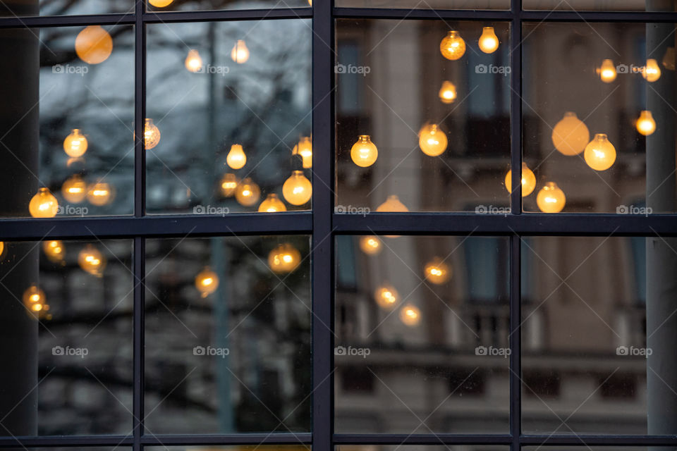 Christmas blurred decorative holiday lights through the window with city street reflection in glass and bokeh effect in background