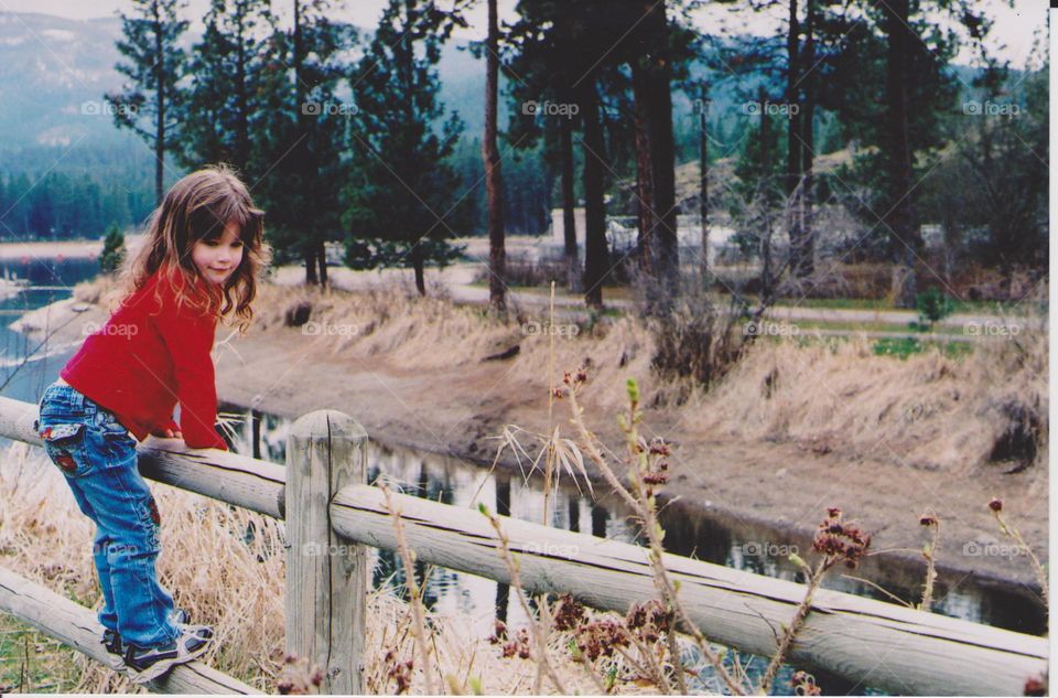 Little girl standing on wooden railing