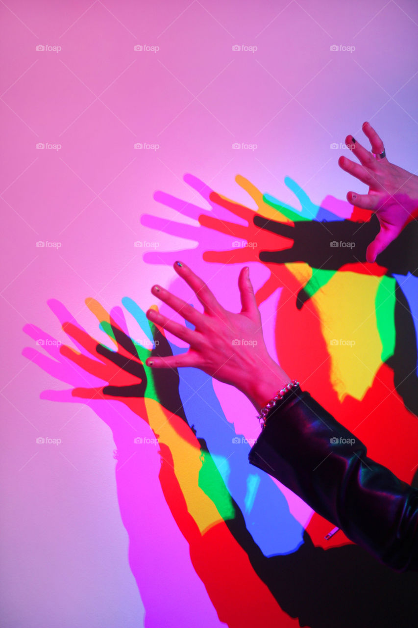 Colorful shadows of hands on the wall