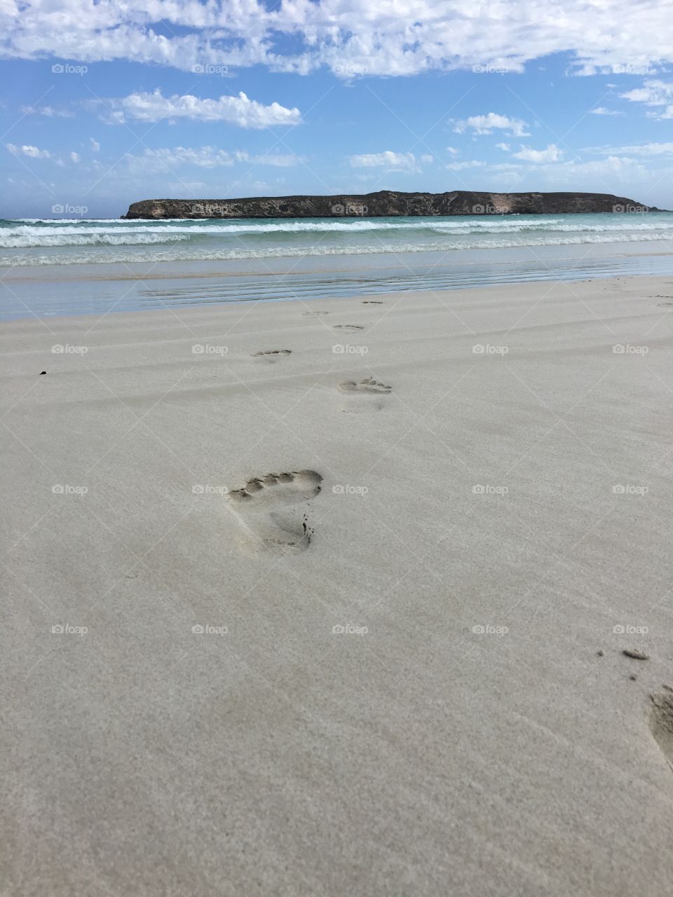 Footprints in the sand leading to ocean surf