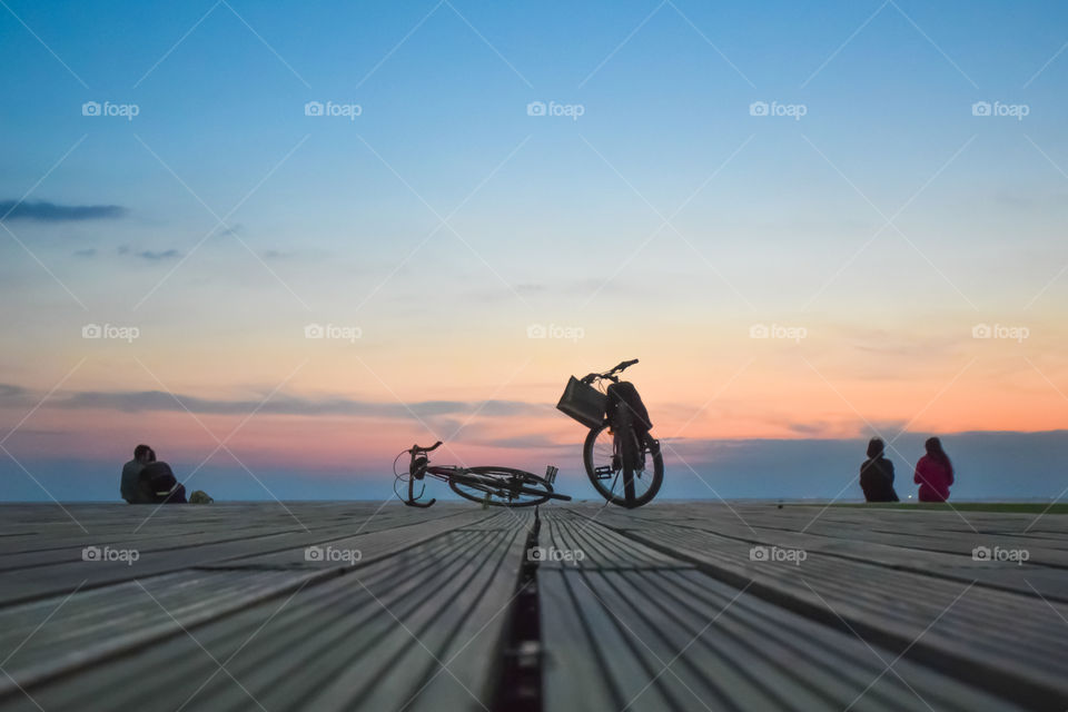 People Sitting On The Dock Enjoying The Sunset
