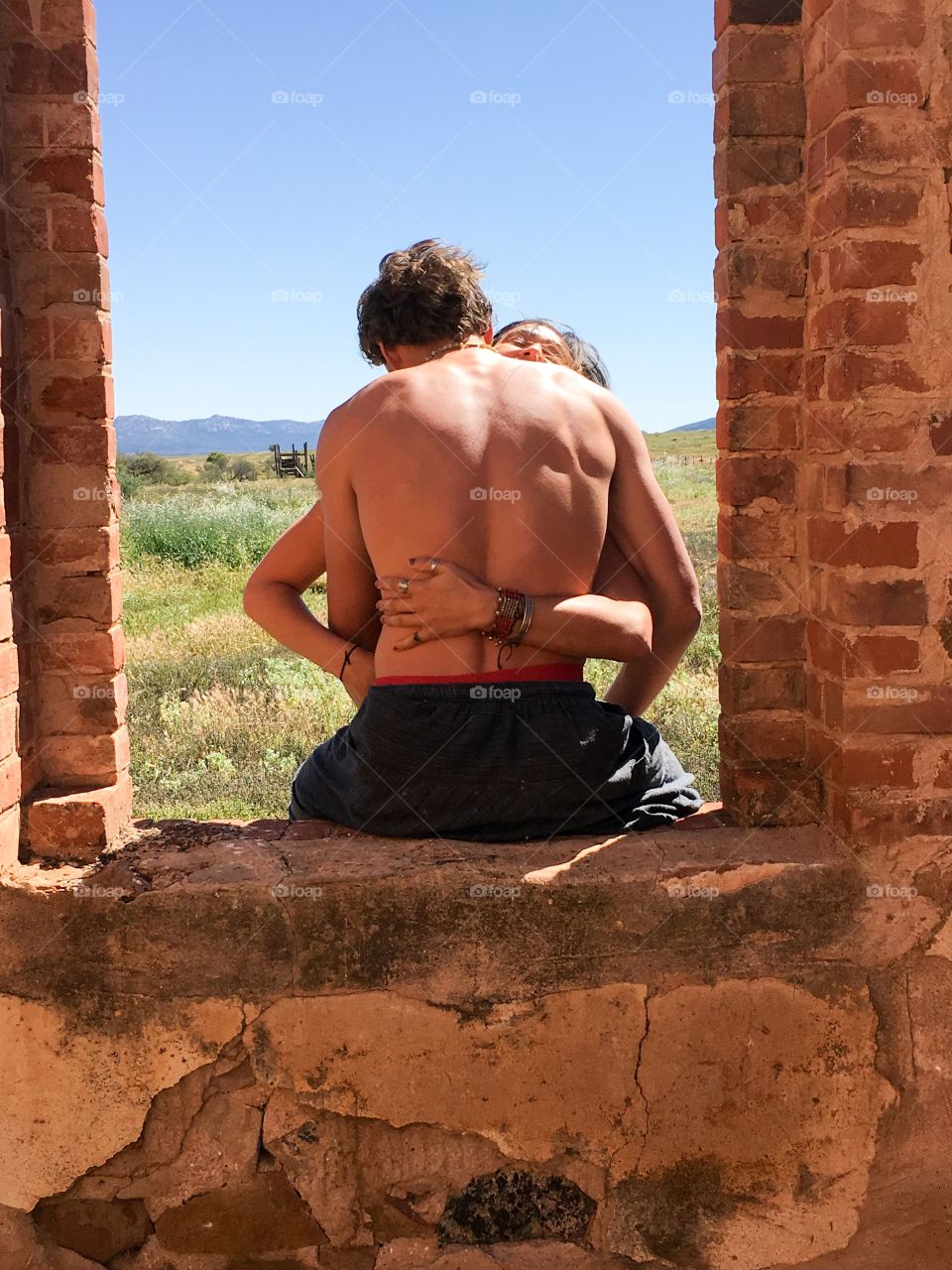 Teenage lovers necking kissing in an embrace in a window portal of an old abandoned stone colonial homestead near the flinders Ranges in south Australia 