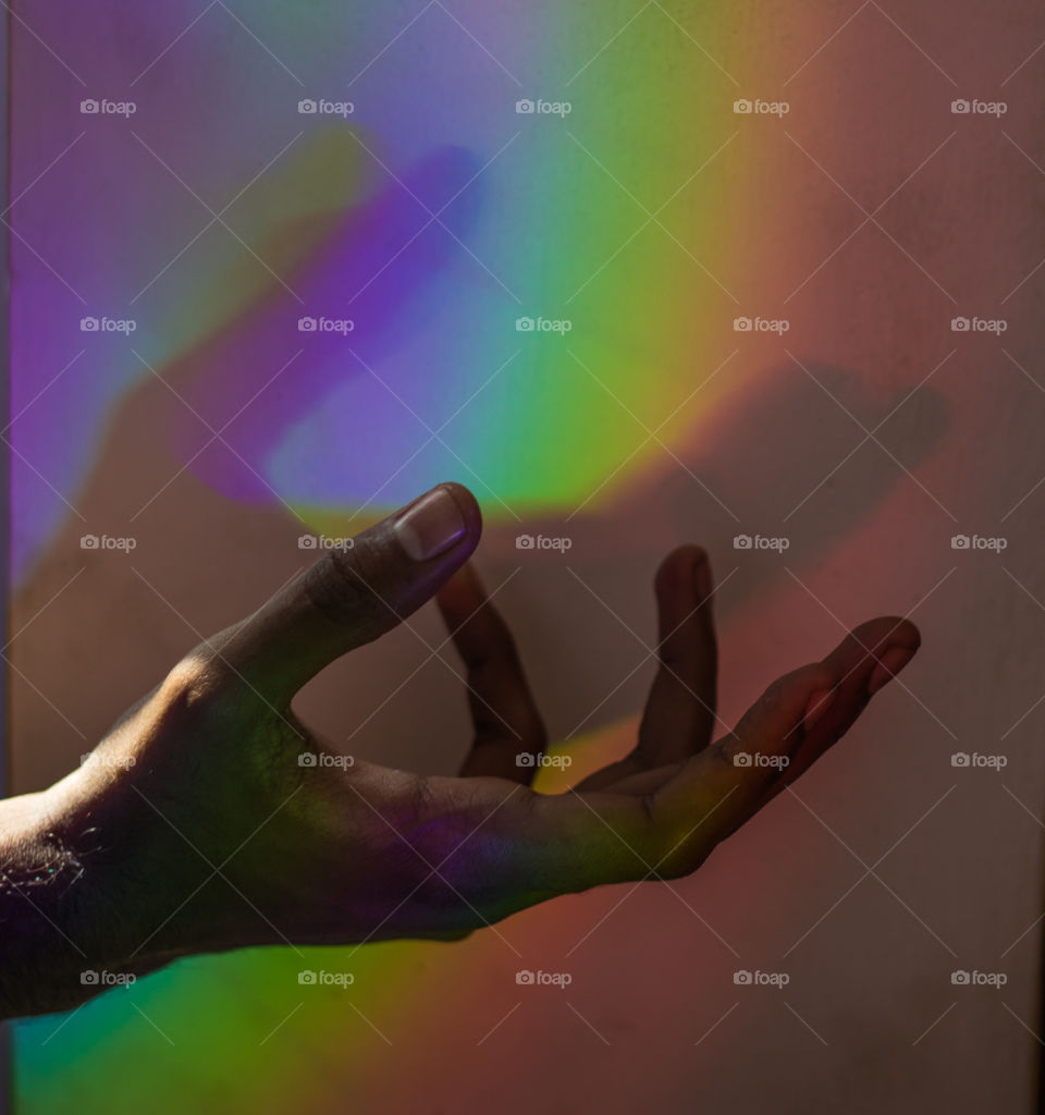 A PICTURE OF A HAND IN A RAINBOW COLOR REFLECTION AT A VILLAGE IN KANNIYAKUMARI, TAMILNADU, INDIA 