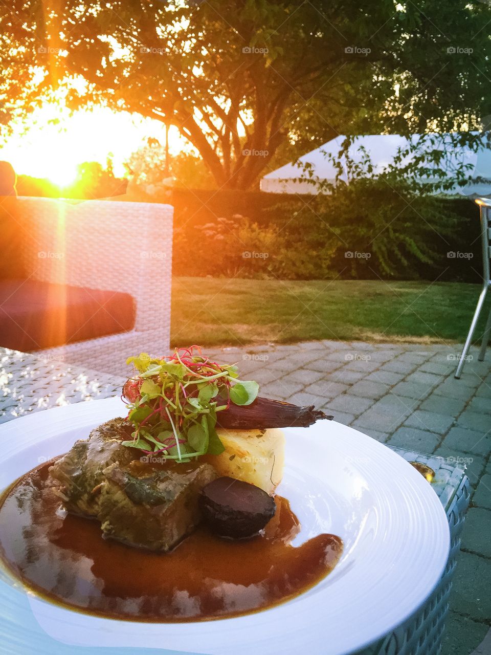 Exclusive main course of fillet of beef and potato cake and gravy, eaten on the terrace at sunset.