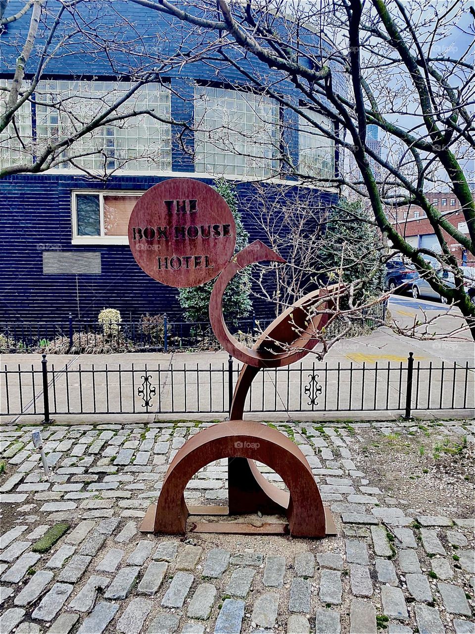 To advertise its presence in “Greenpoint”, Bklyn at “Newtown Creek” by the “Pulaski Bridge” the  “BOXHOUSE Hotel” added a futuristic looking art object, a wooden sculpture sign right in front of the building. 2023. Hypnotic Productions