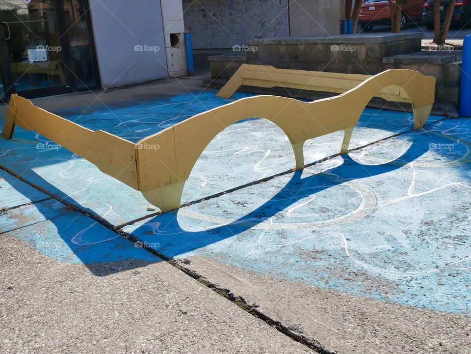 A pair of giant yellow sunglasses sitting in a painted pool of water. 