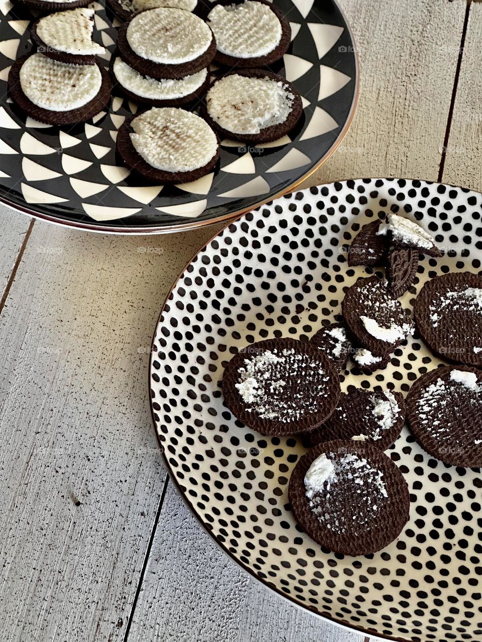 “Unscrewed” Oreo cookies showing brown cookie and white center filling on black-and-white patterned plates on whitewashed boards 