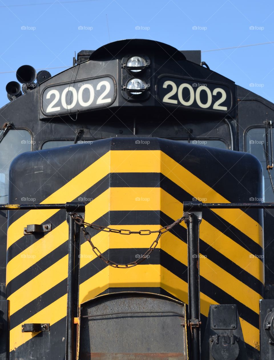 Front of black train engine marked with bright yellow stripes
