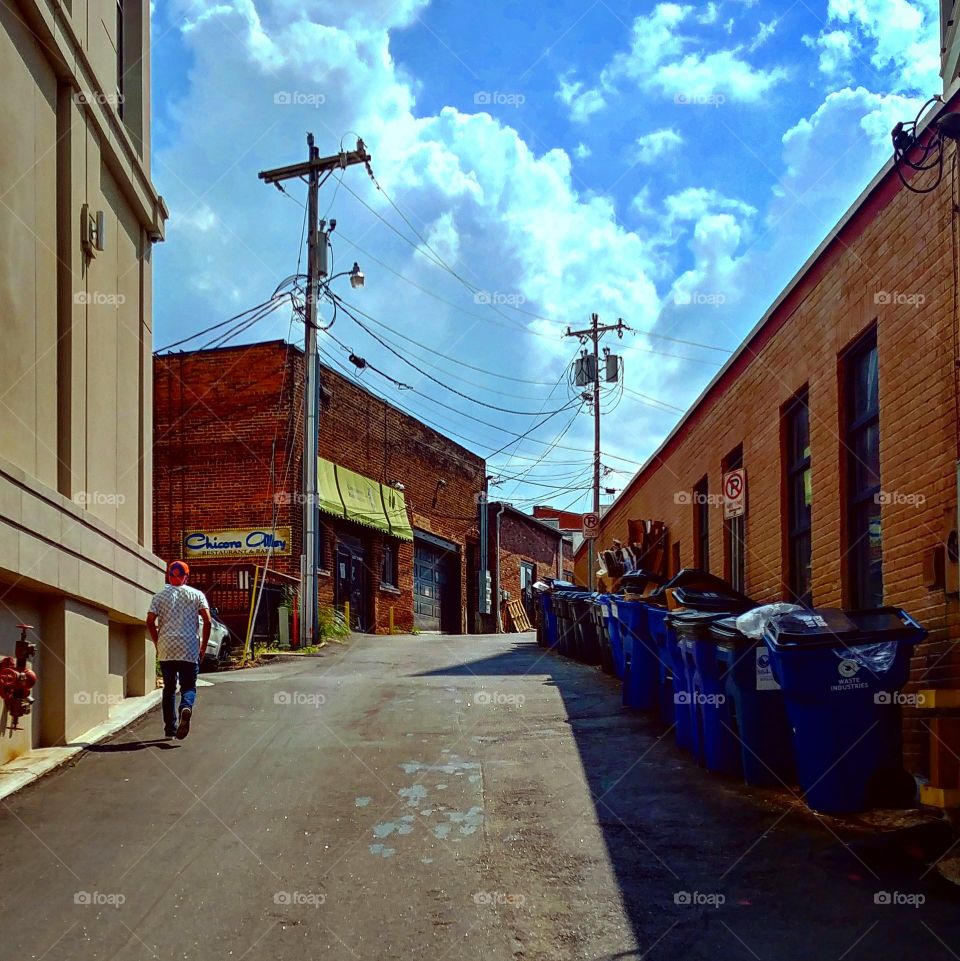 An organic alleyway with recycling bins and a person in Greeneville South Carolina