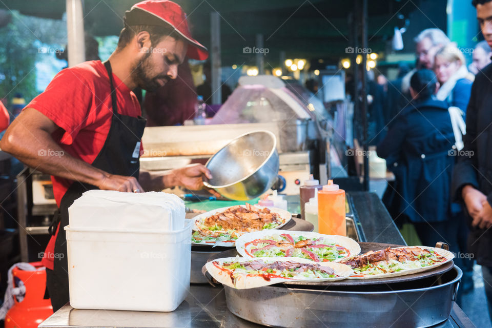 A cook in a food stalls cooking at a food market in Borough Market in London.