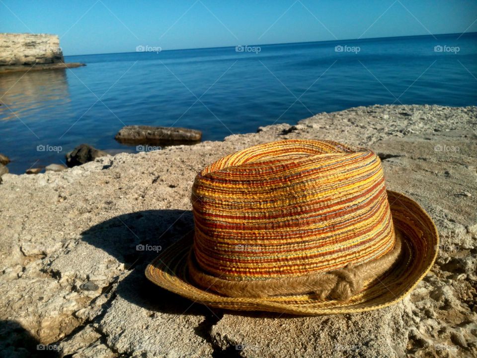 Close-up of sun hat on rock at sea