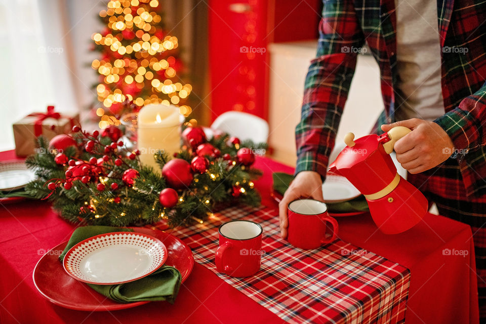 Festive winter cozy kitchen interior with garlands, decorations and gifts.  Christmas dinner at the decorated table.