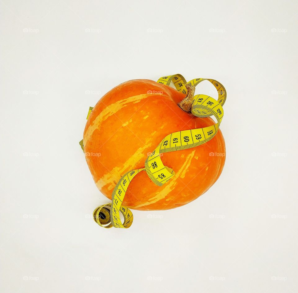 Pumpkin belted centimeter ribbon on white background, diet, healthy lifestyle