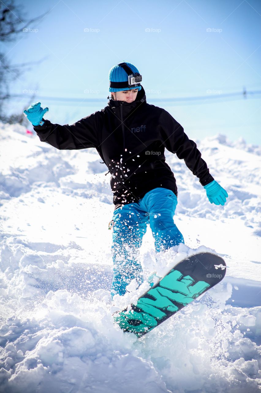 Man snowboarding on snowy field against sky during winter