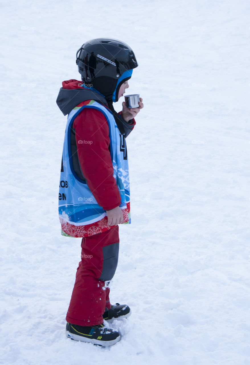 the little athlete drinking from a thermos of coffee in the winter