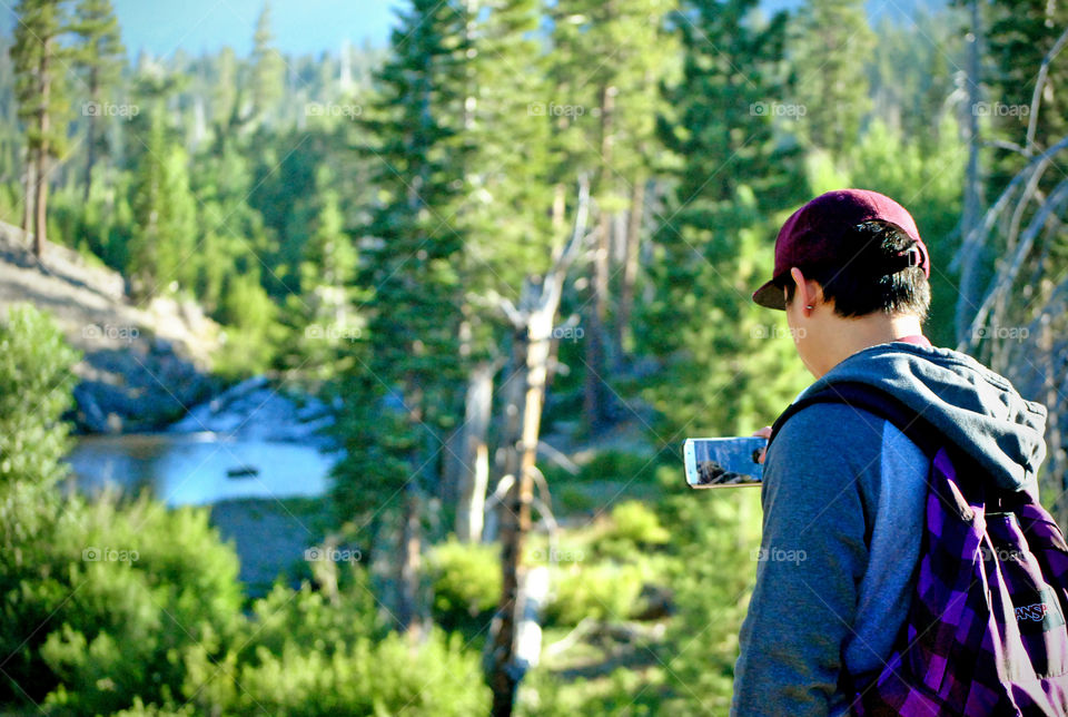 man taking a photo of the water stream using mobile phone as camera