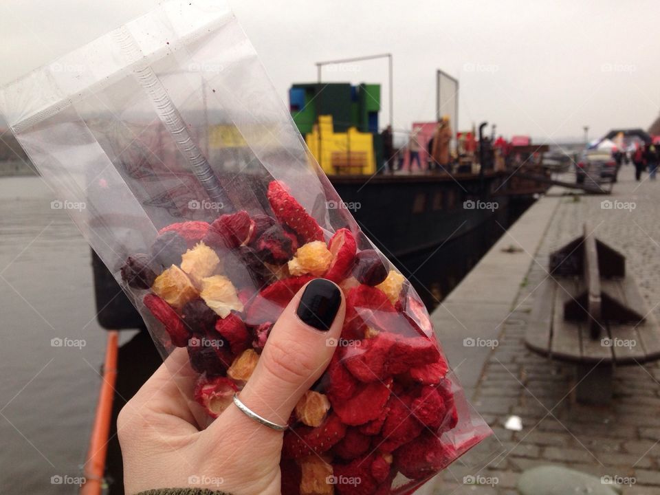 my hand with packing of berries and fruits on the quay in Prague
