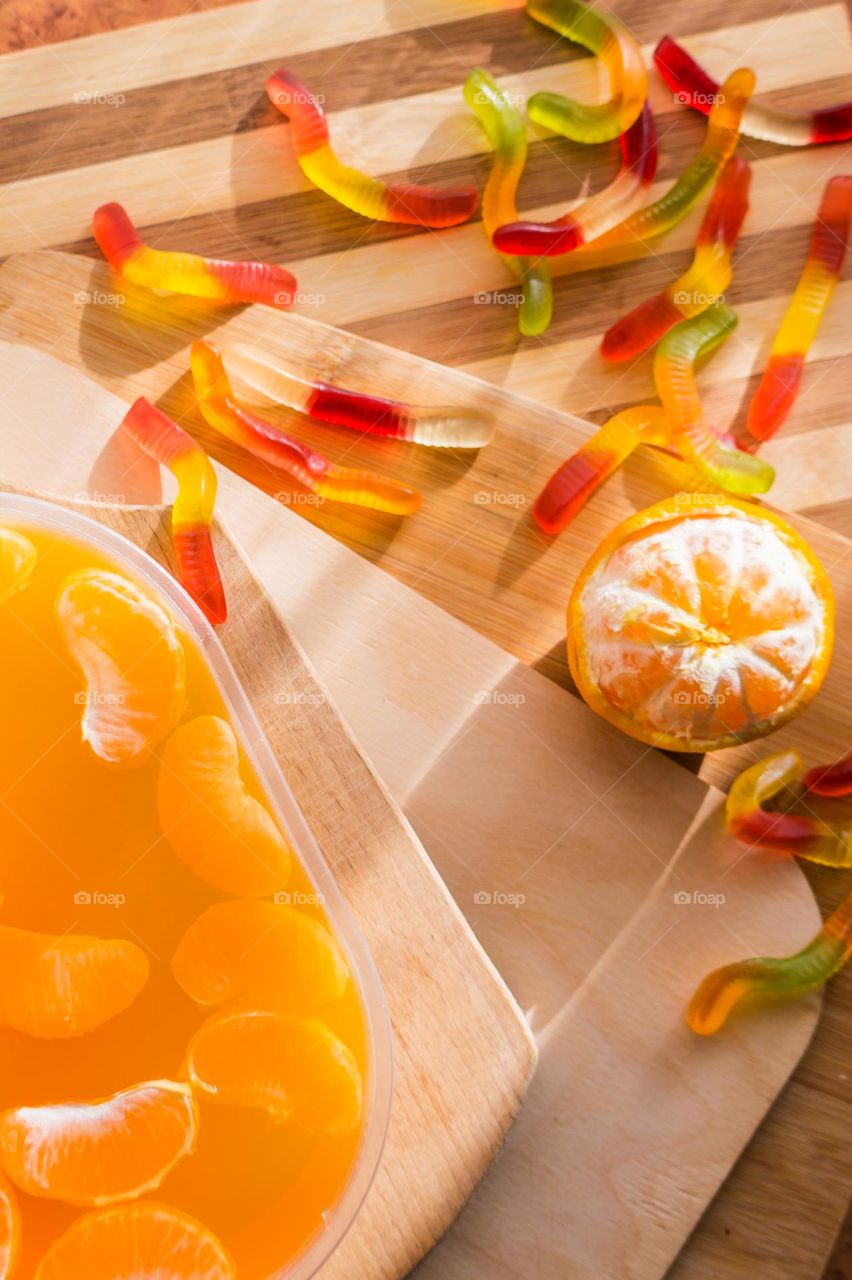 Delicious orange jelly with tangerine slices in a container and jelly worms.