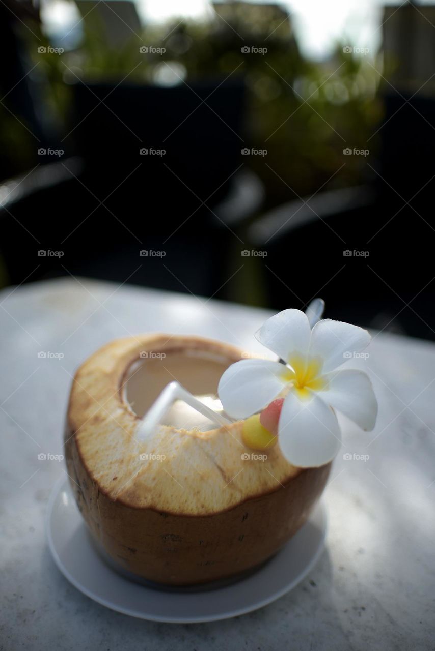 Young coconut fruit decorated with frangipani flowers, one of the typical drinks that are suitable on the beach during summer vacation