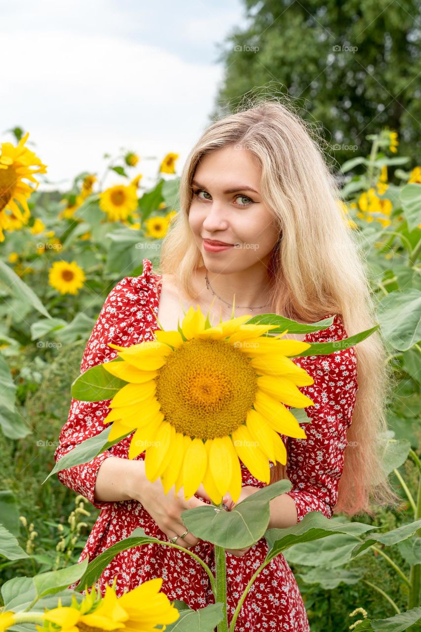 a girl with long blond hair stands in a field of sunflowers