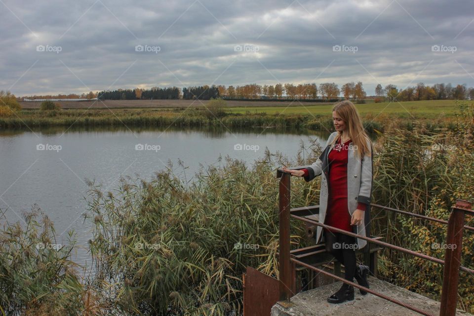 The girl stands by the lake in autumn. Autumn landscape.