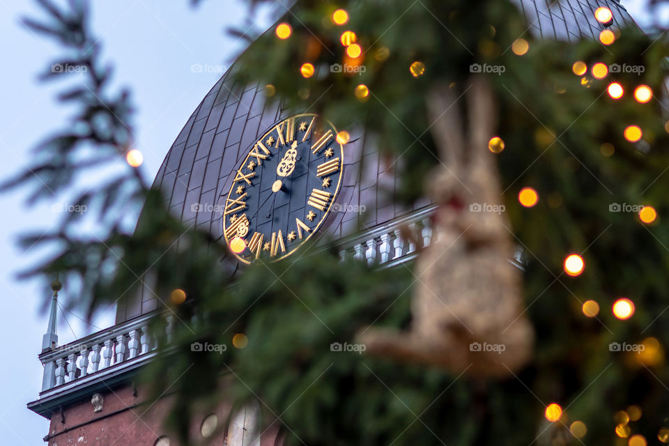 Christmas decorations and lights. In the background clock in church tower,