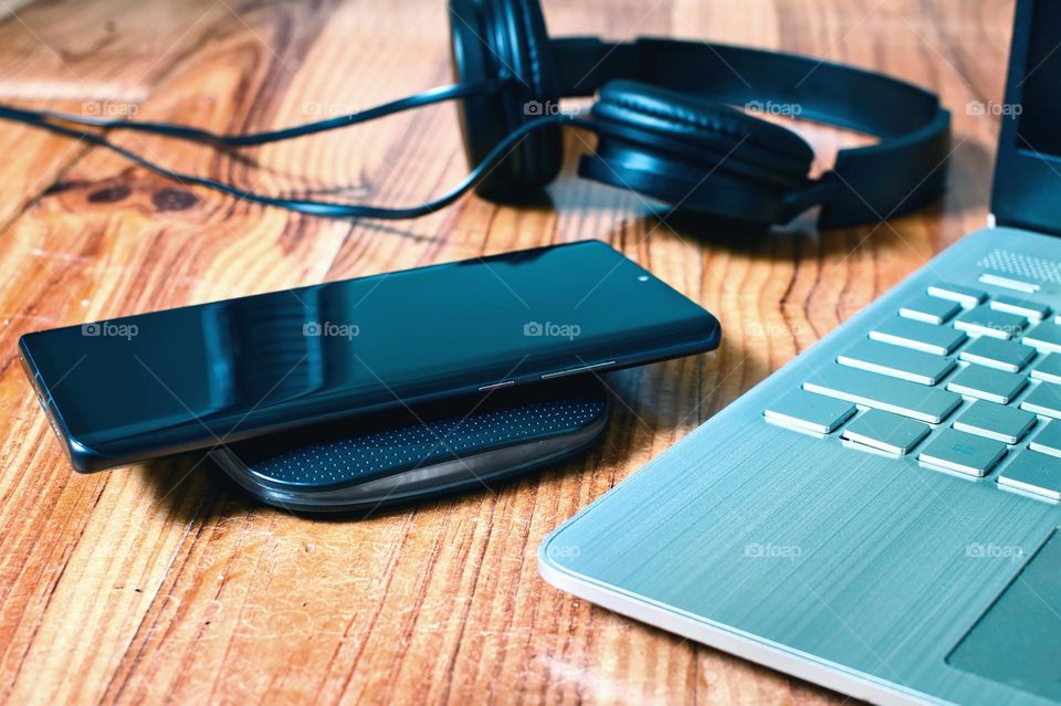 smartphone on wireless charger in office on wooden desk