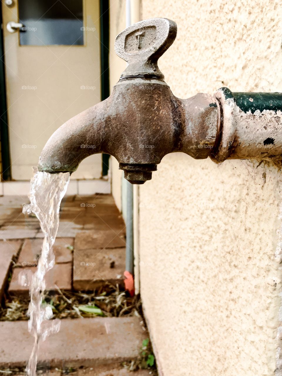 Outdoor water faucet tap spigot pipe, antique, vintage old iron, water flowing, turned on 