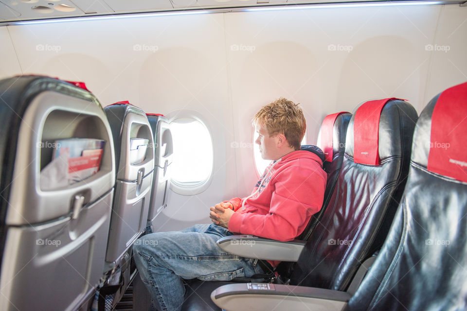 Male passager in a airplane looking out the window.