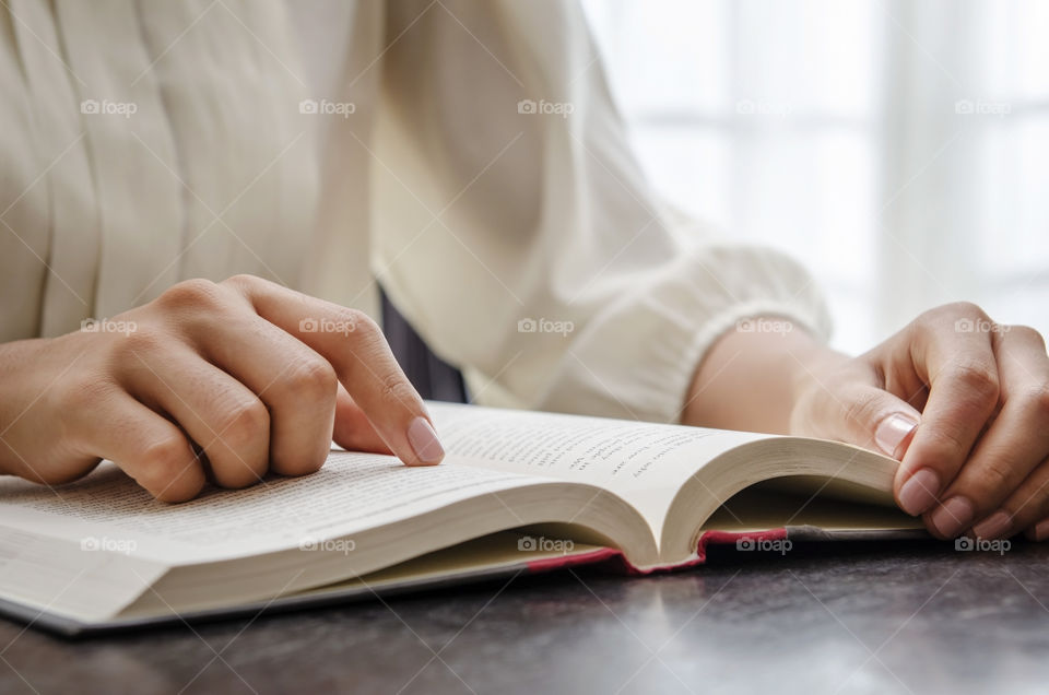 Woman reading a book, with her finger funning through it 