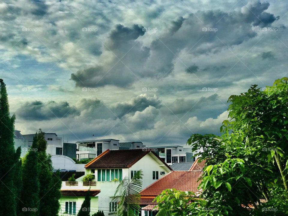 A beautiful and colourful clouds look like a flying animal in the sky and a beautiful ancient individual houses along with greenery under the clouds looks amazing