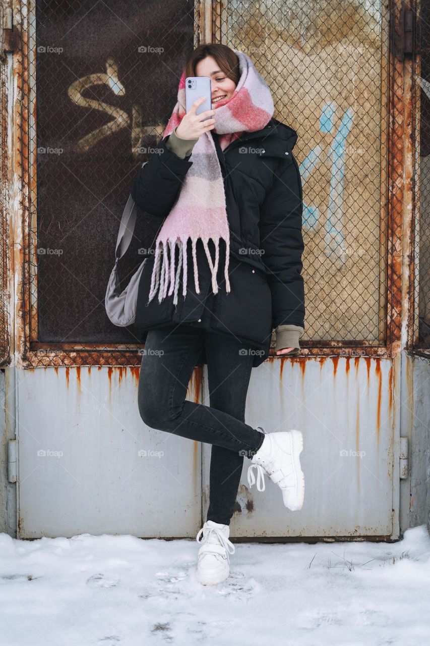 Young woman with mobile phone in white Dr. Martens boots in winter 