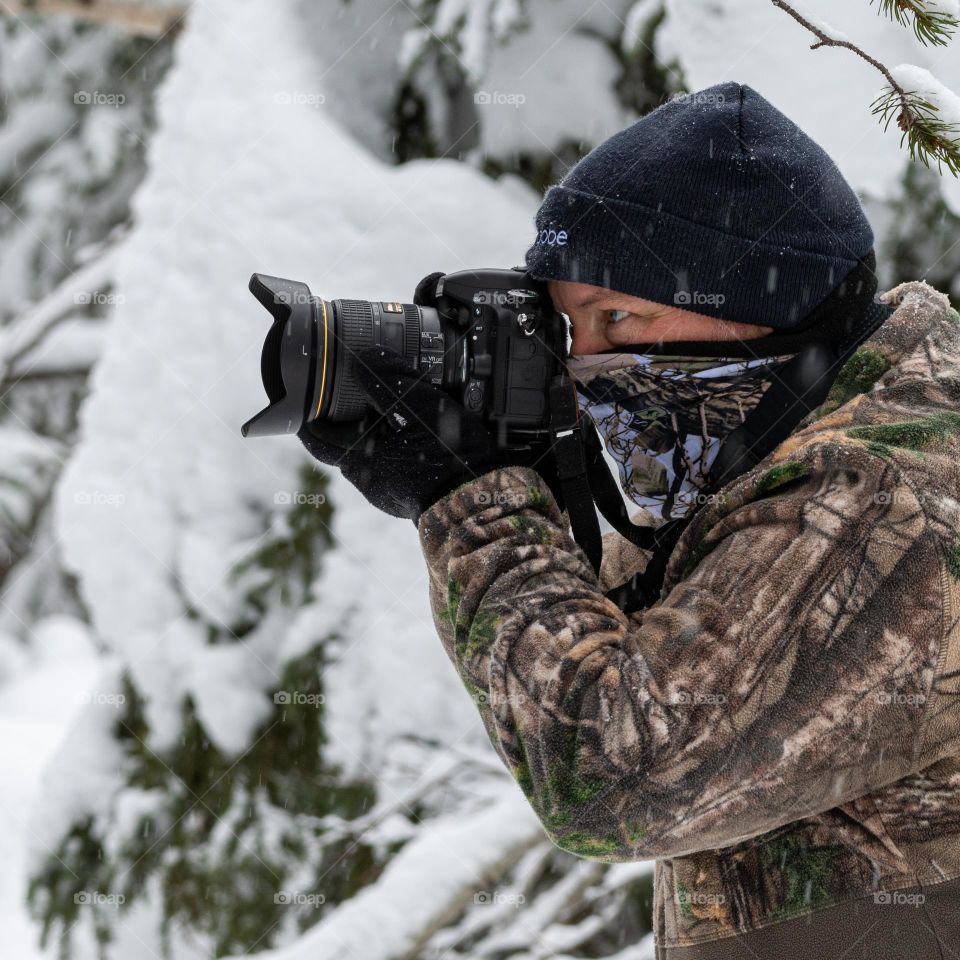 Wildlife photographer in camouflage suit in winter