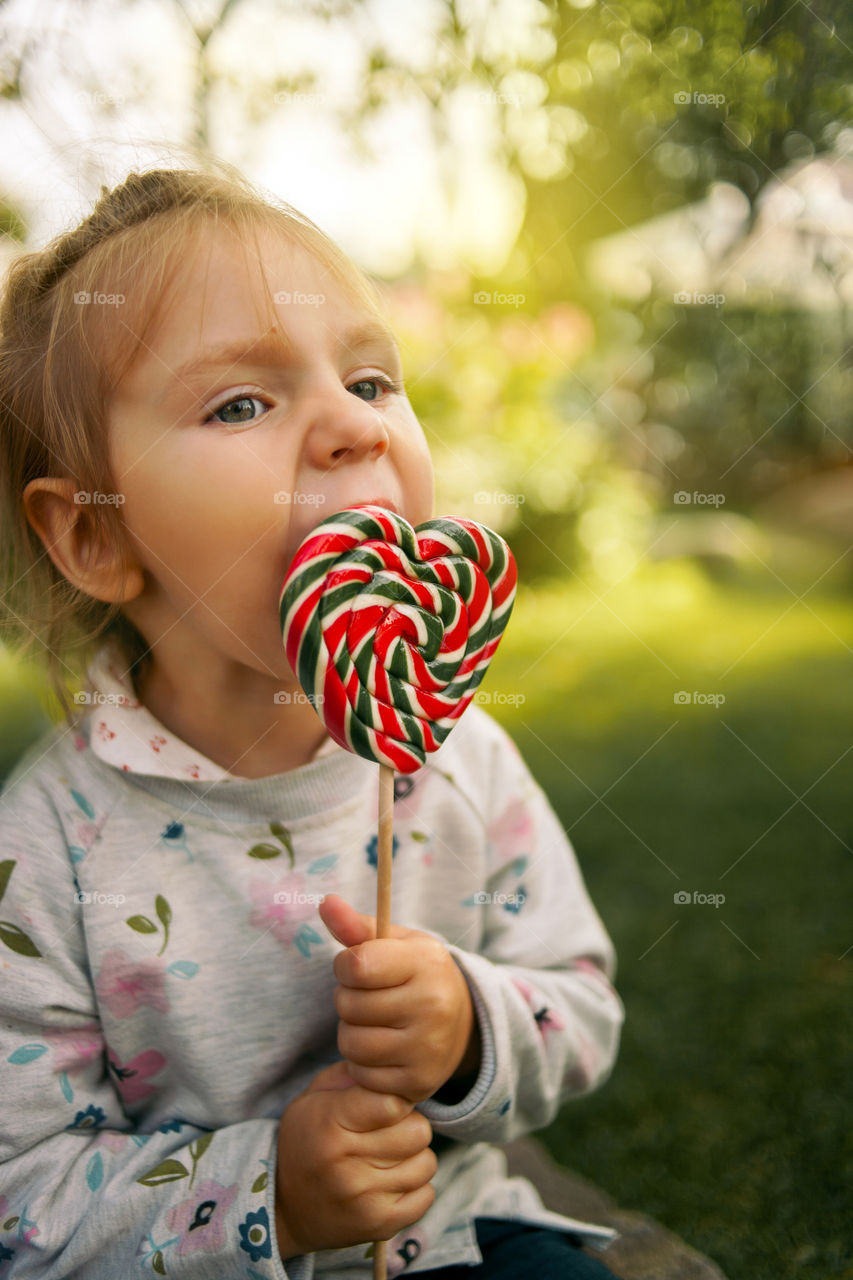 Cute little girl eating lollipop 