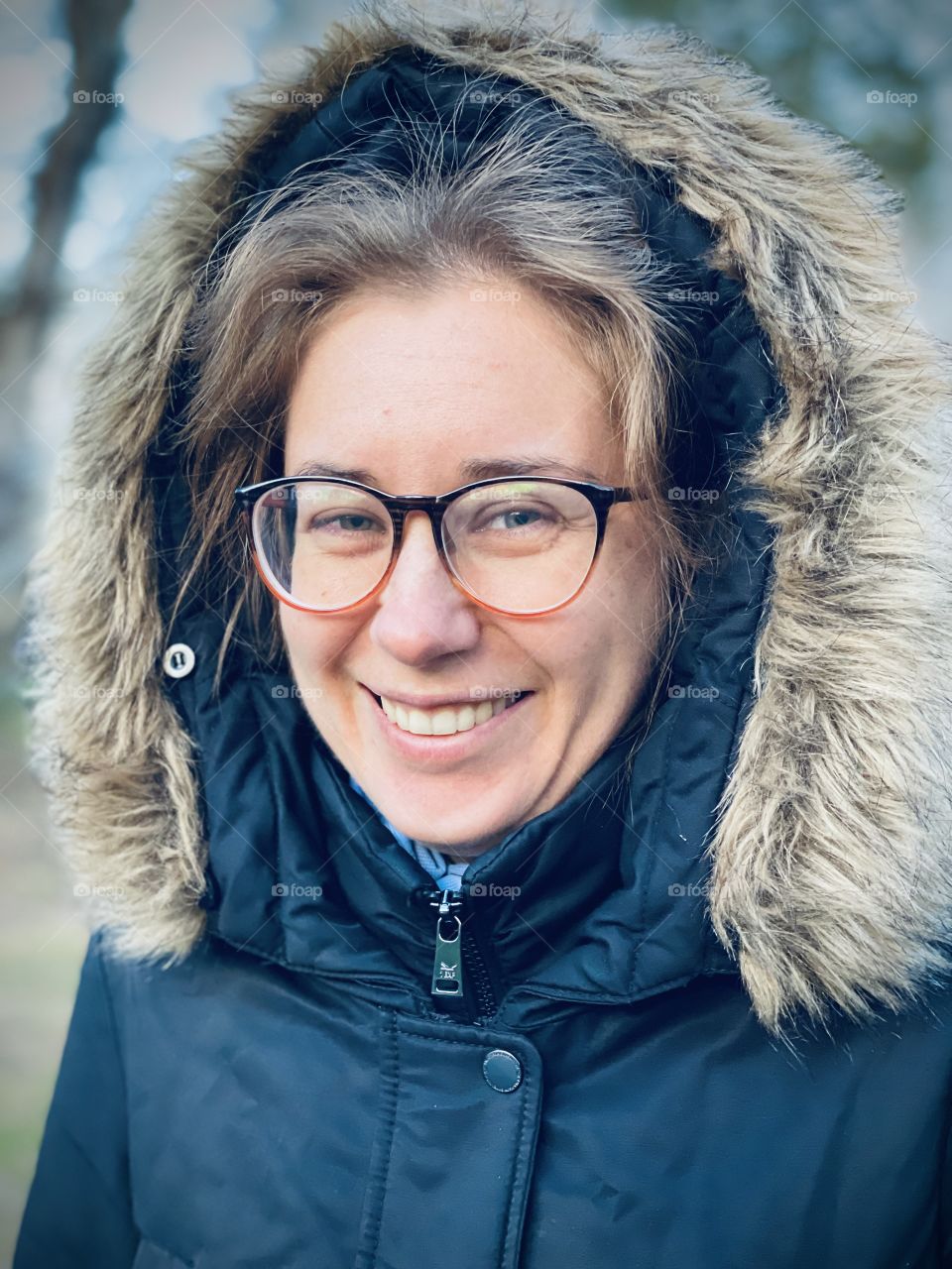 A woman in winter coat and glasses laughing 