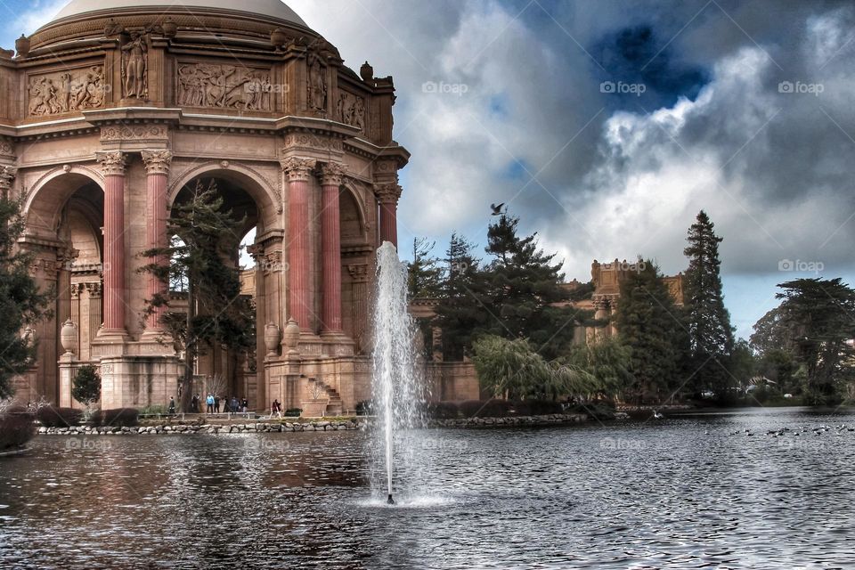 Vintage looking image of the landmark Palace of Fine Arts in San Francisco California with the fountain rising through the lagoon on a warm sunny afternoon with clouds in the sky 