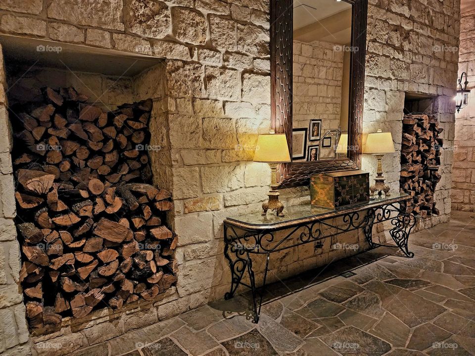 Stacks of fragrant firewood envelope a delicate cast iron and glass table accented with warm glowing table lamps