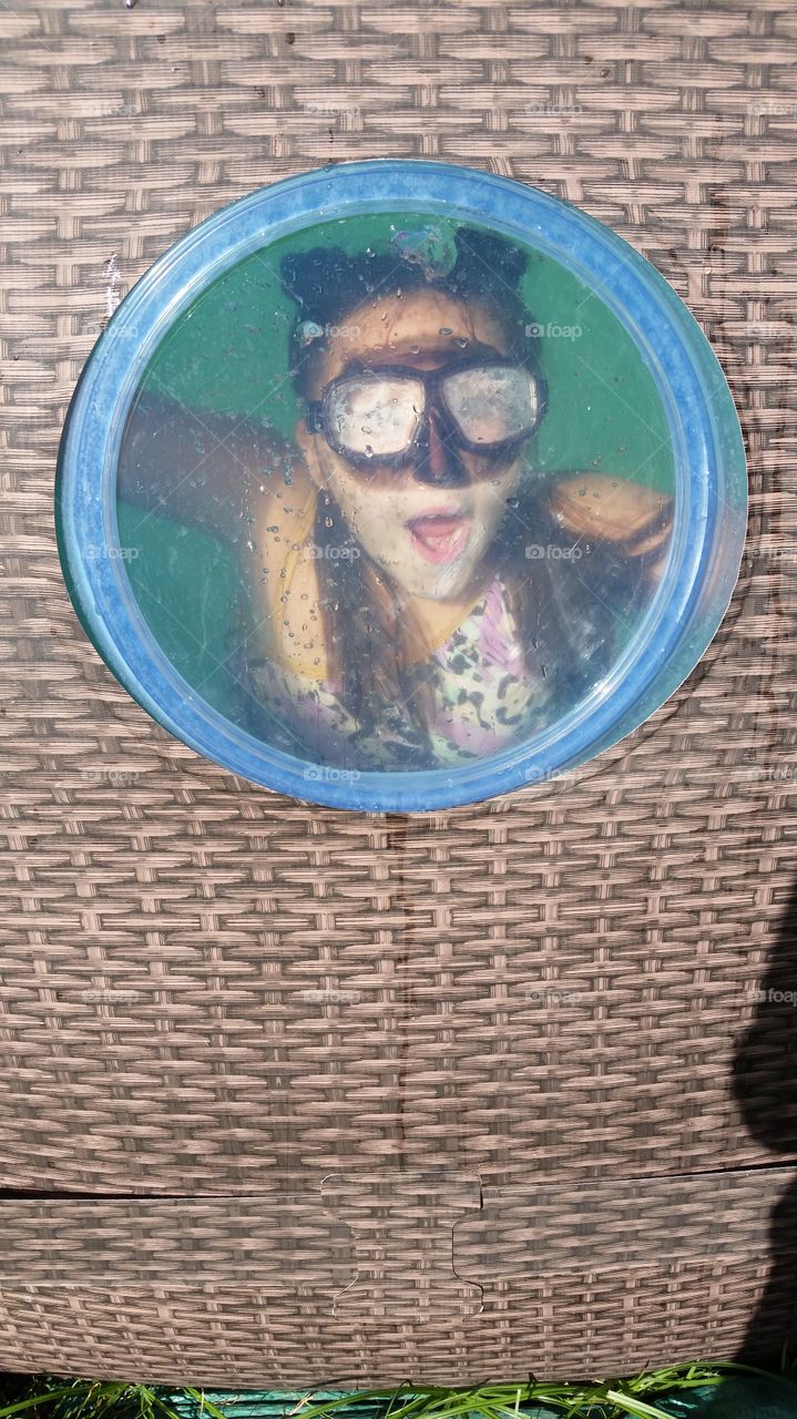 Little girl underwater at the swimming pool window!