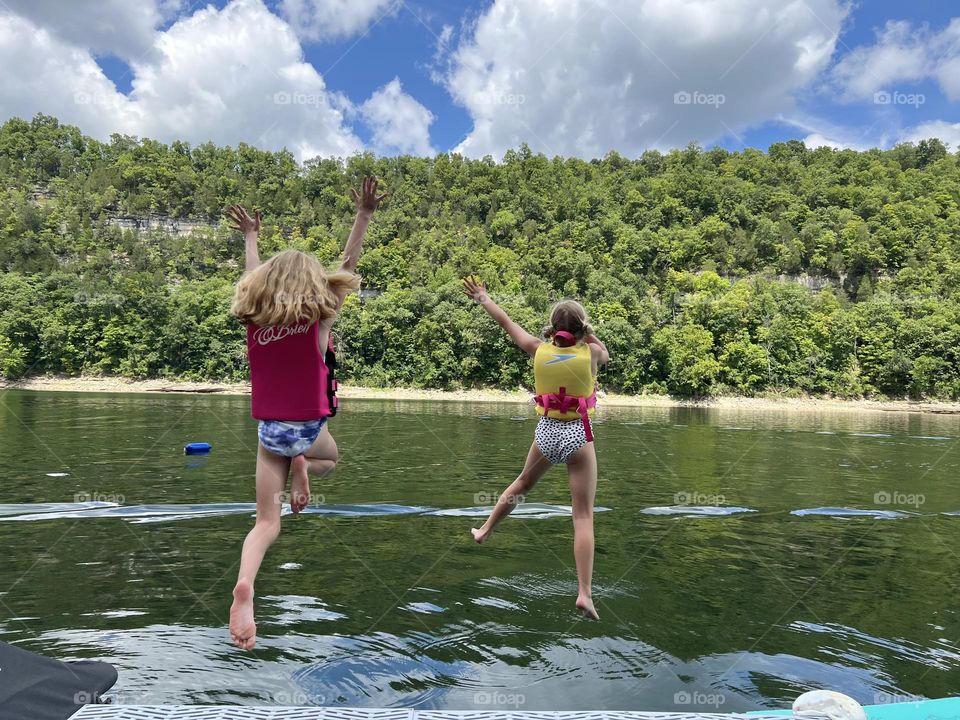 Two little girl friends making childhood memories jumping into Lake Cumberland.